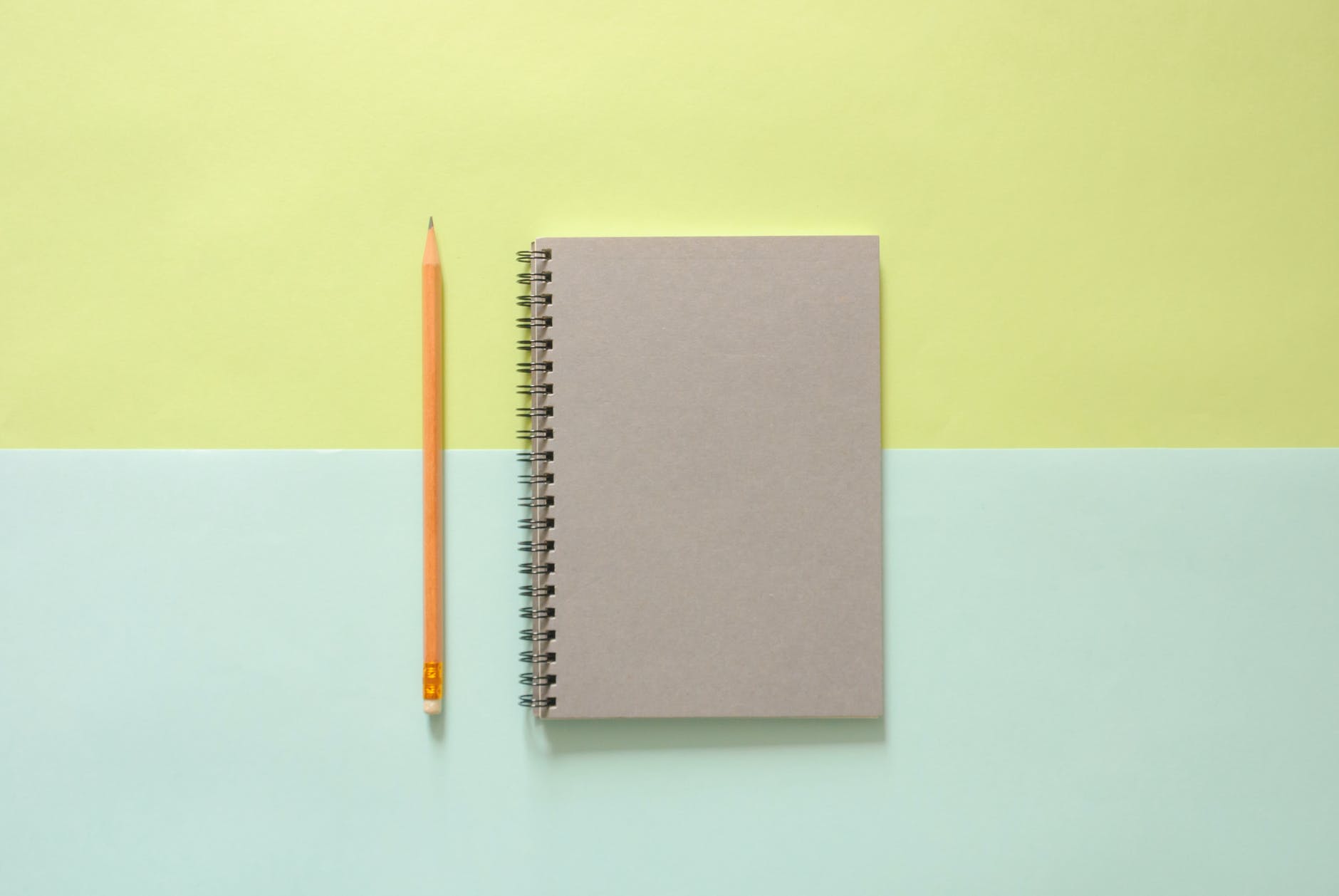 white spiral notebook beside orange pencil